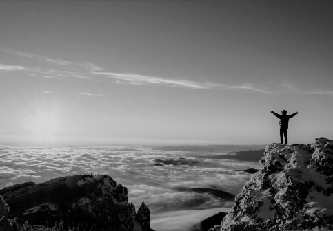 Man standing on top of mountain over the clouds
